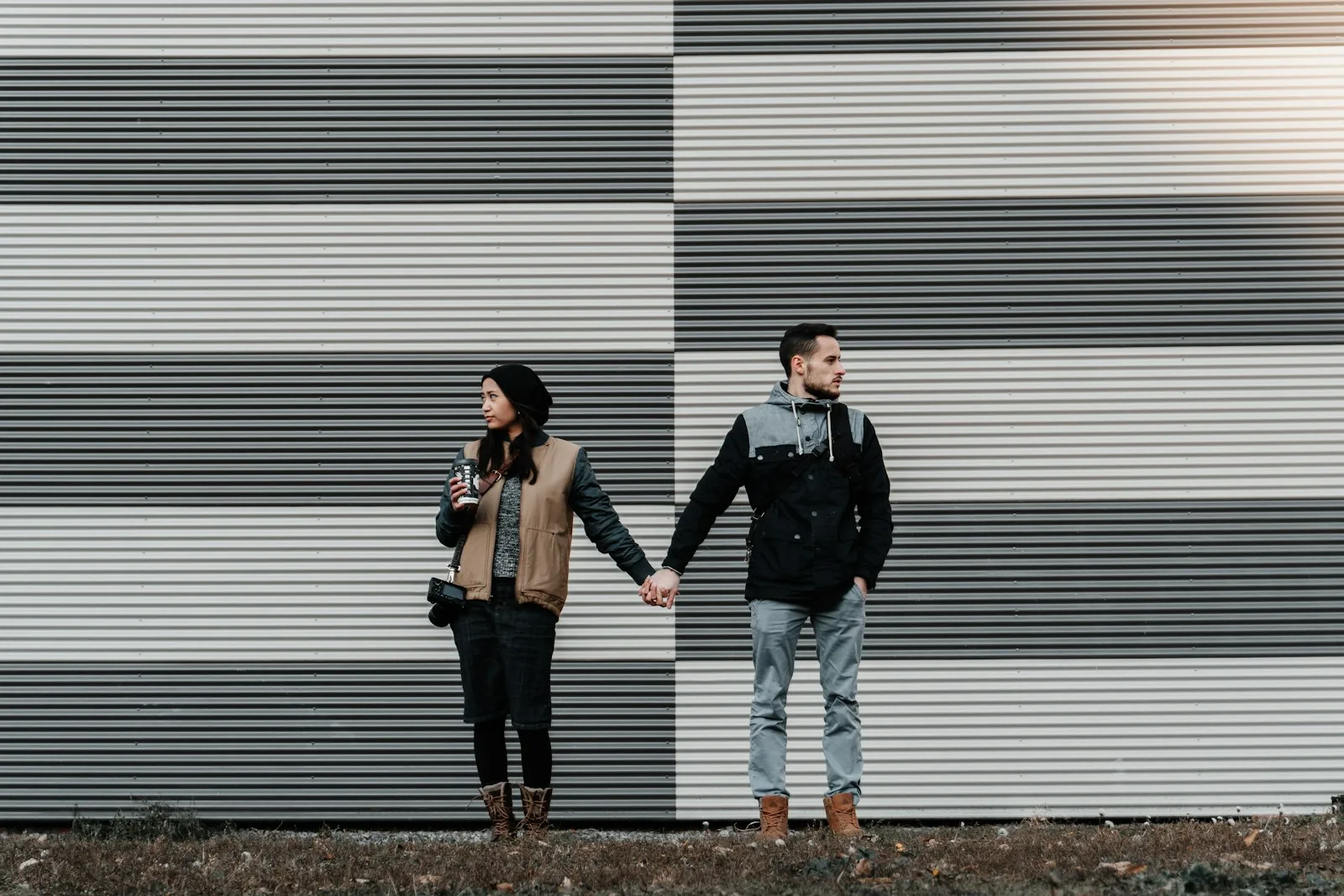 Couple holding hands against stripes.